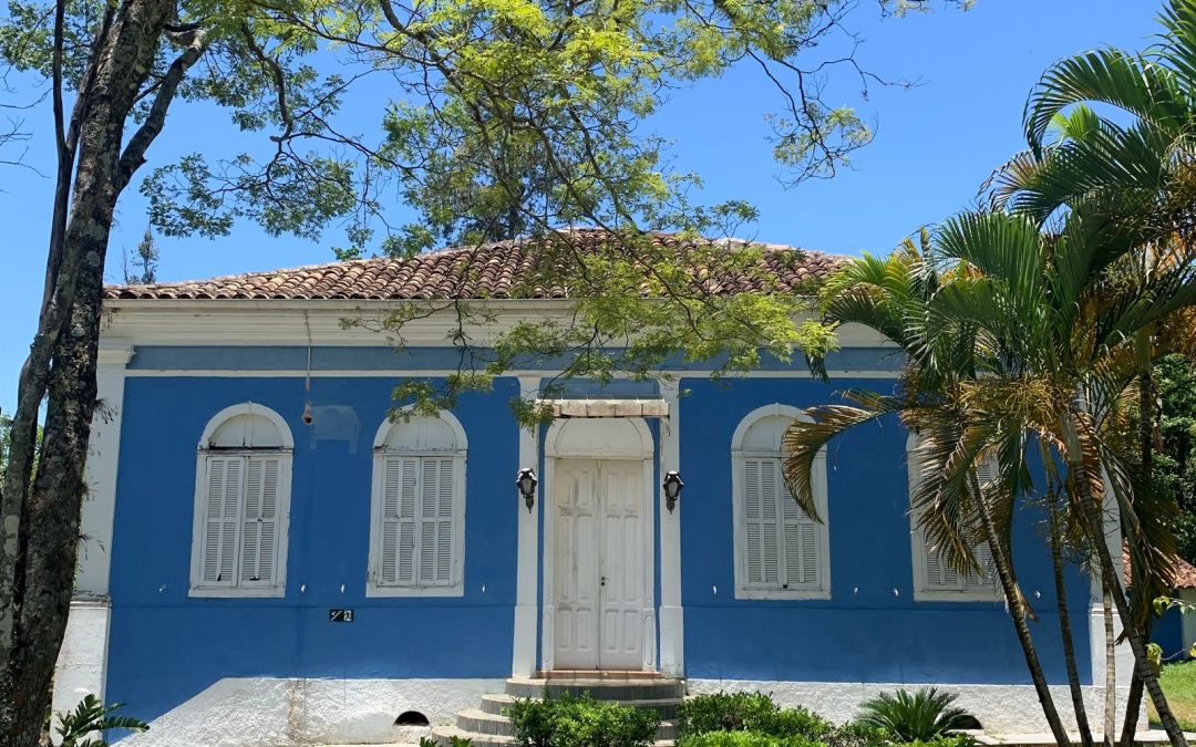 Maison de style colonial aux murs bleus entourée de verdure