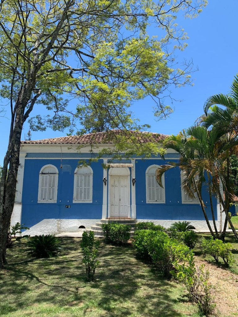 Maison de style colonial aux murs bleus entourée de verdure